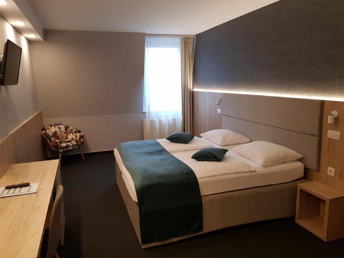 Twin beds with white linens and teal throw in modern hotel room with desk