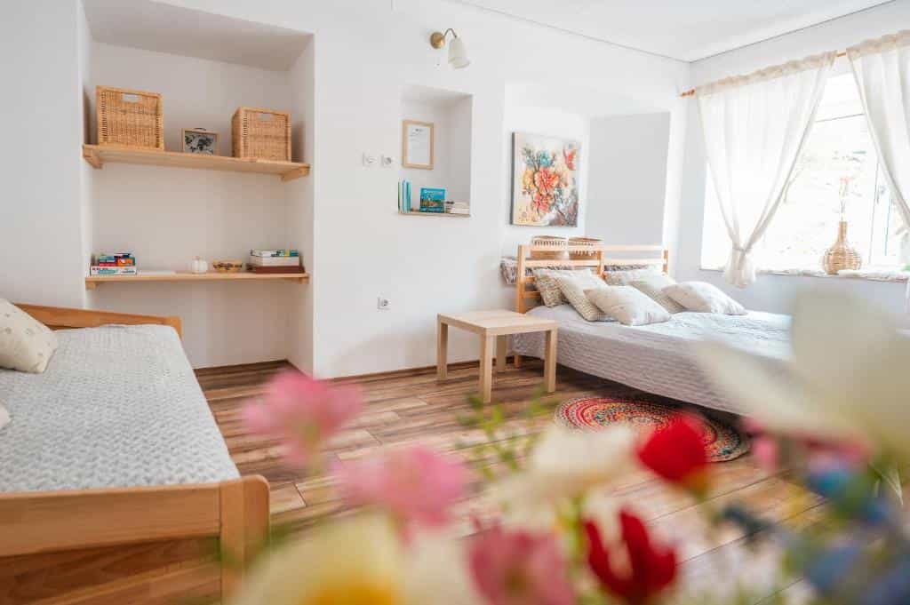 Bright bedroom with wooden beds, white walls, and flowers in the foreground.