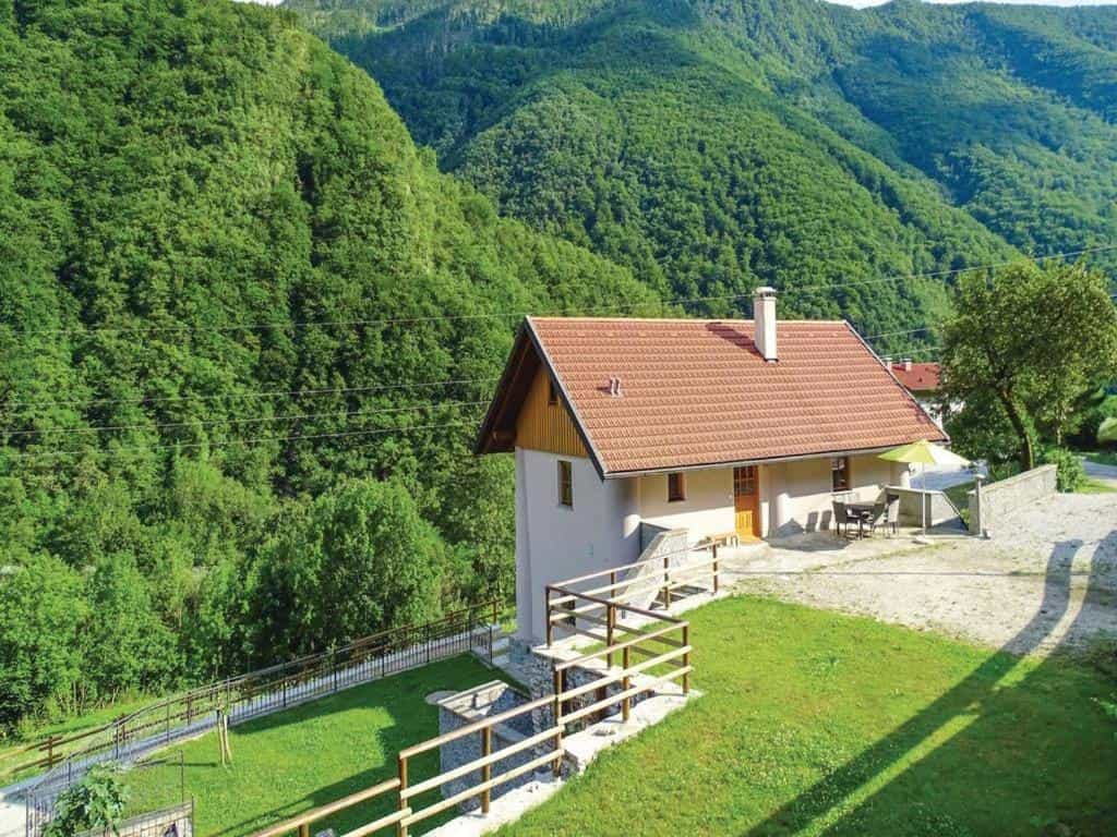House with terracotta roof set against steep, lush green forested mountains
