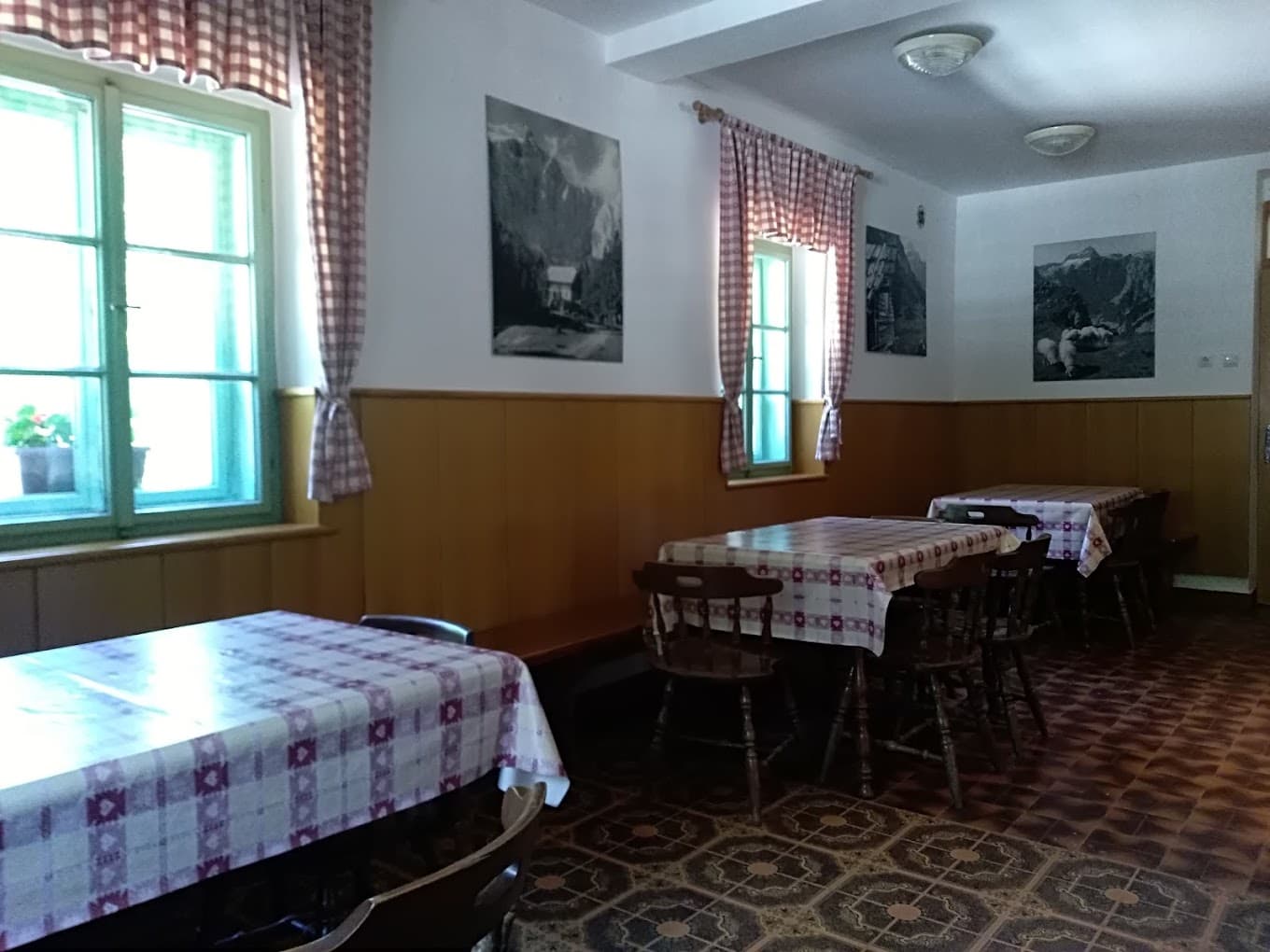 Dining room with checkered tablecloths, wood paneling, and mountain photos, Aljažev Dom v Vratih