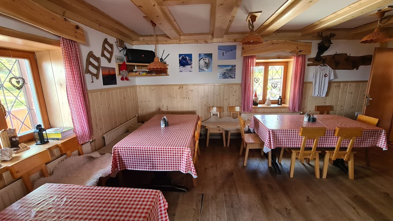 Interior of Blejska koča na Lipanci mountain hut with wooden walls and red gingham tablecloths.