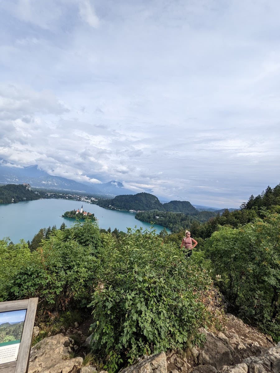 Hiker overlooking Lake Bled island church and mountains from a rocky viewpoint
