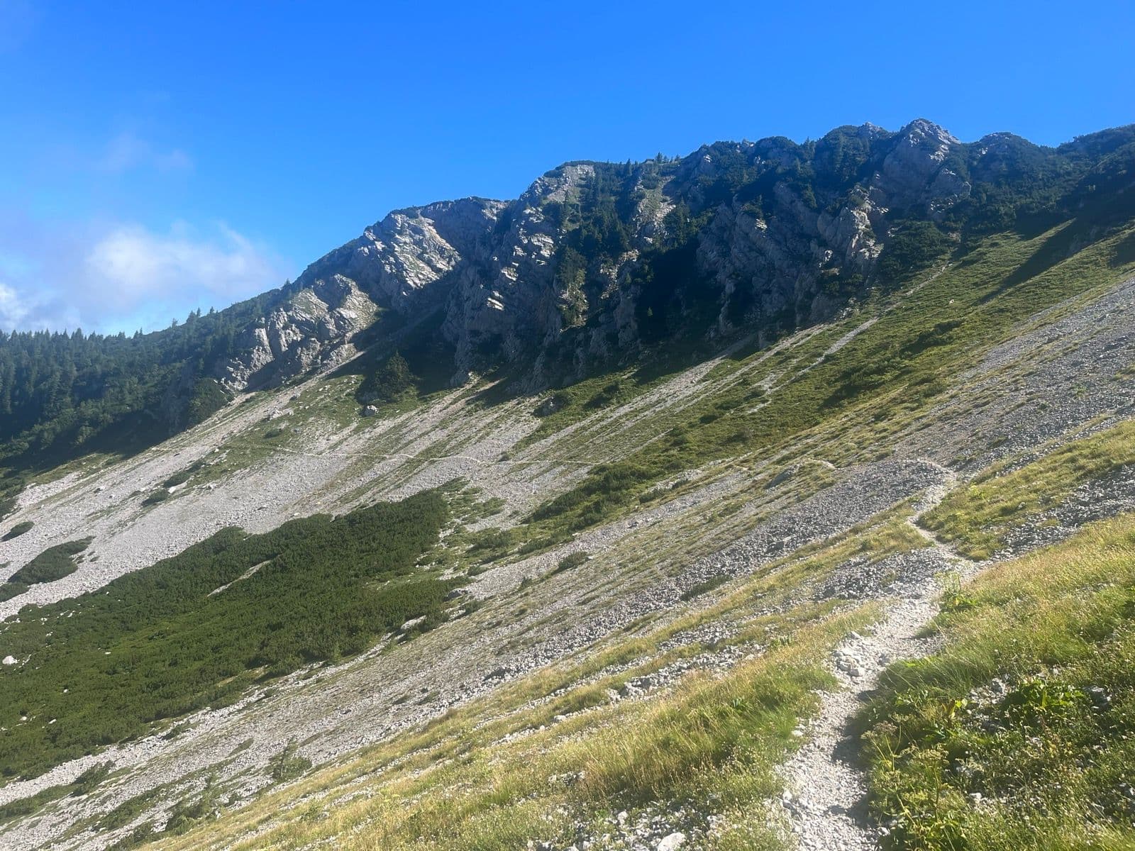 Hiking trail on a rocky mountain slope in the Karawanks under a clear blue sky.