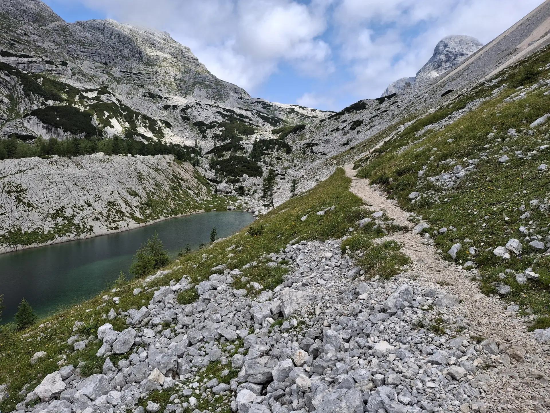 Hiking trail along a mountain lake surrounded by rocky alpine terrain.