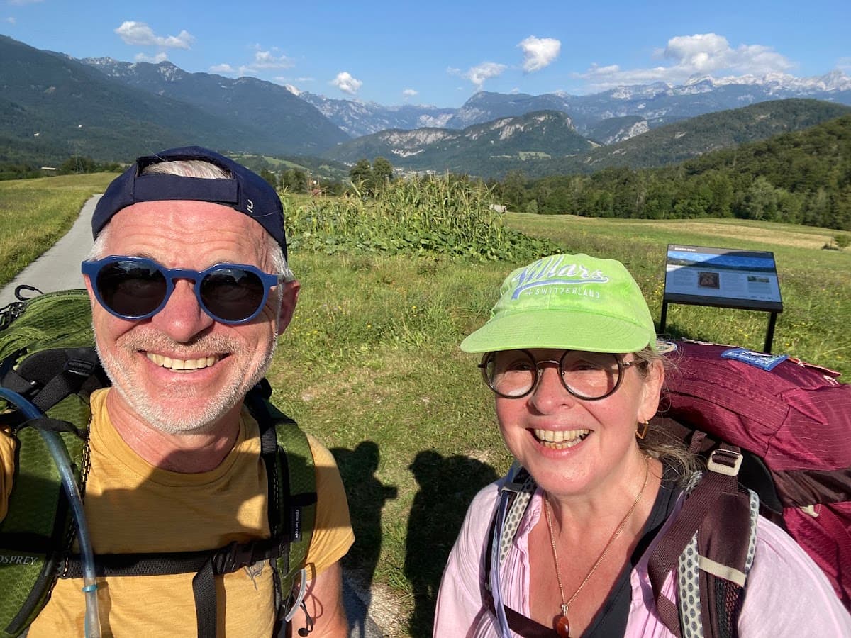 Hikers with backpacks taking a selfie on a trail with mountain background
