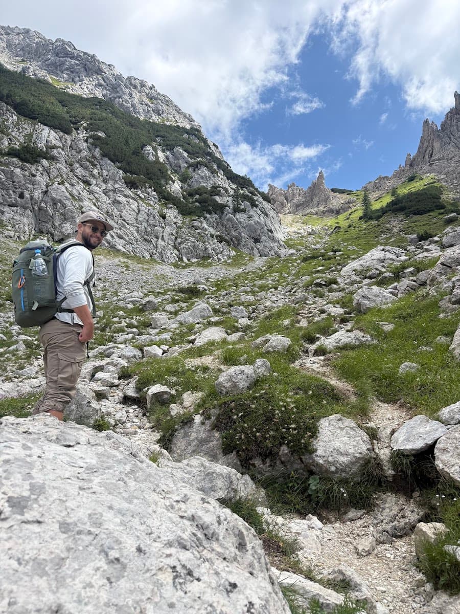 Hiker with backpack on rocky mountain trail under blue sky