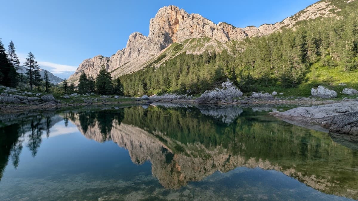 Alpine mountain peaks and pine forest reflected in a clear mountain lake