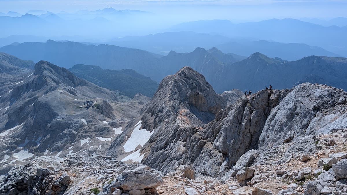 Hikers on rocky mountain ridge with panoramic view of peaks and valleys