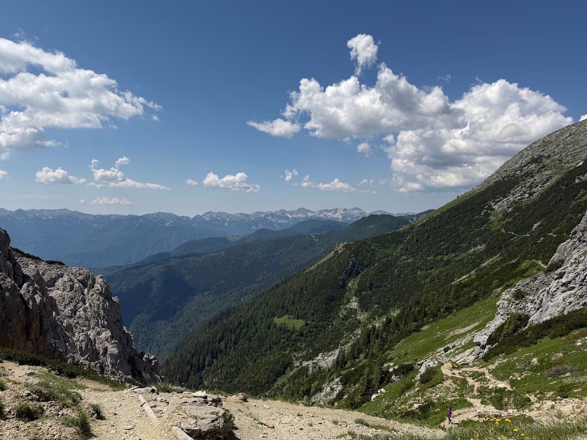 Mountain peaks with green slopes and hiking trail under blue sky with clouds