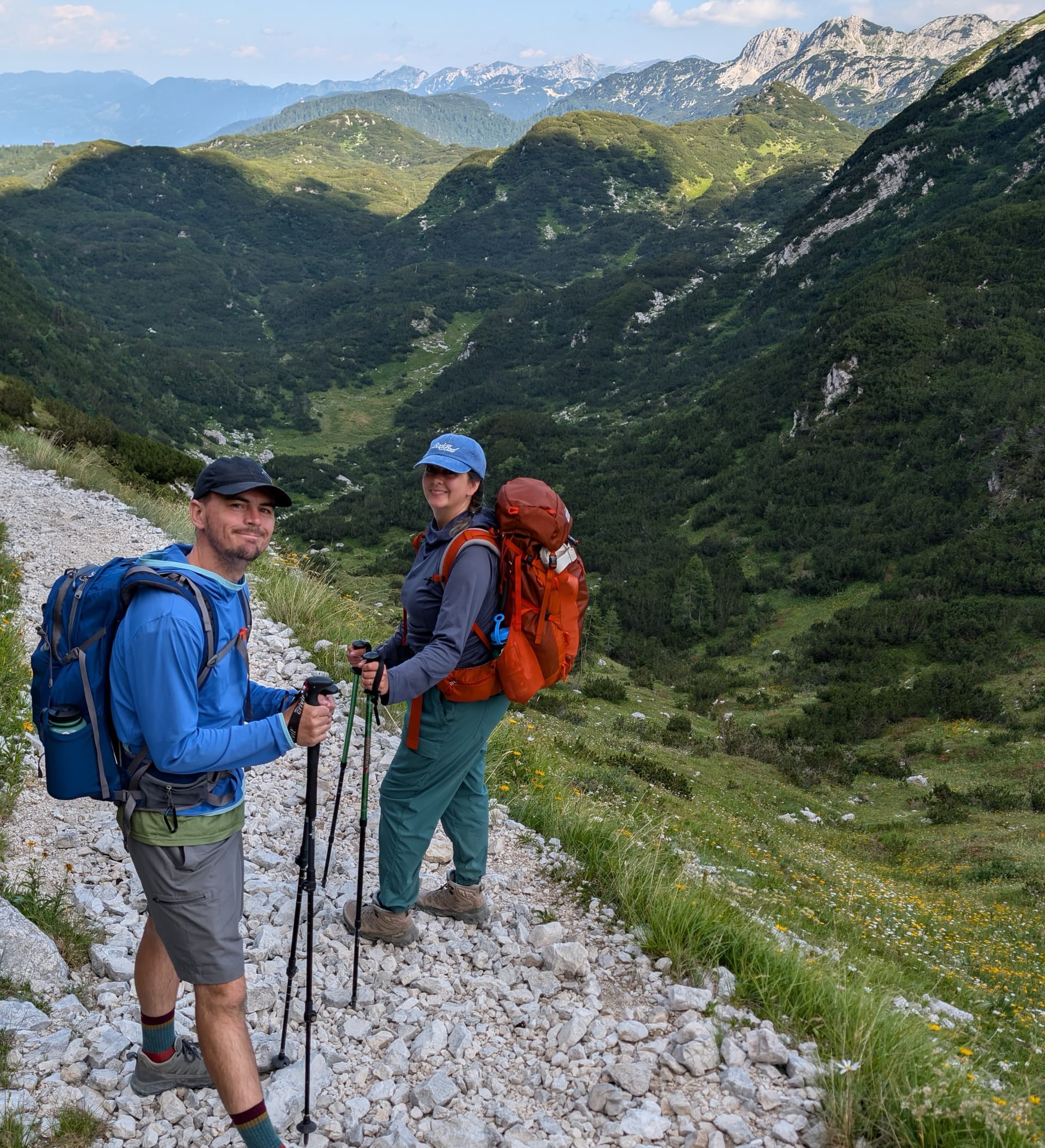 Two hikers with backpacks on a rocky trail in the Julian Alps