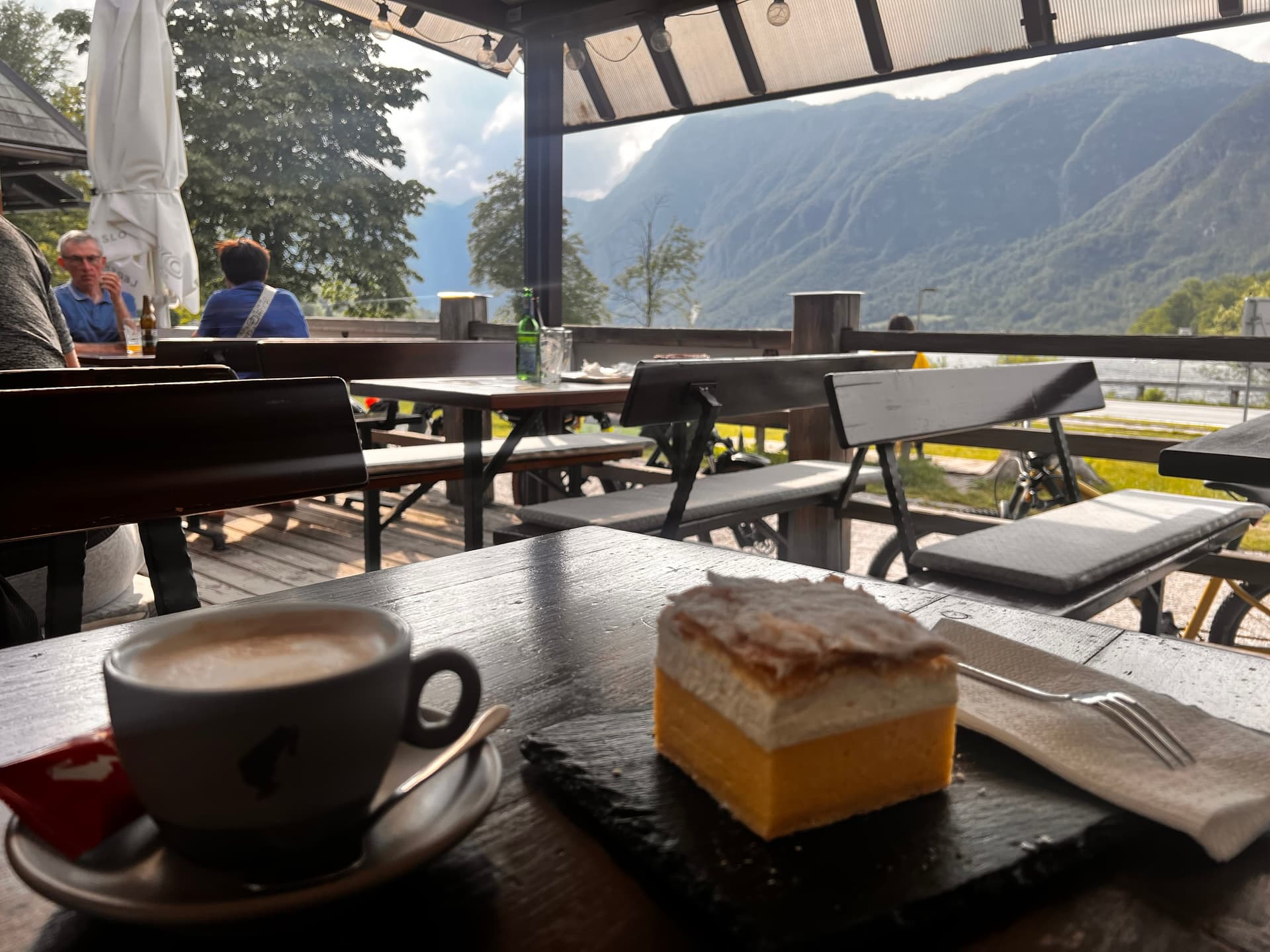 Coffee and cream cake on wooden table at outdoor terrace with mountain view