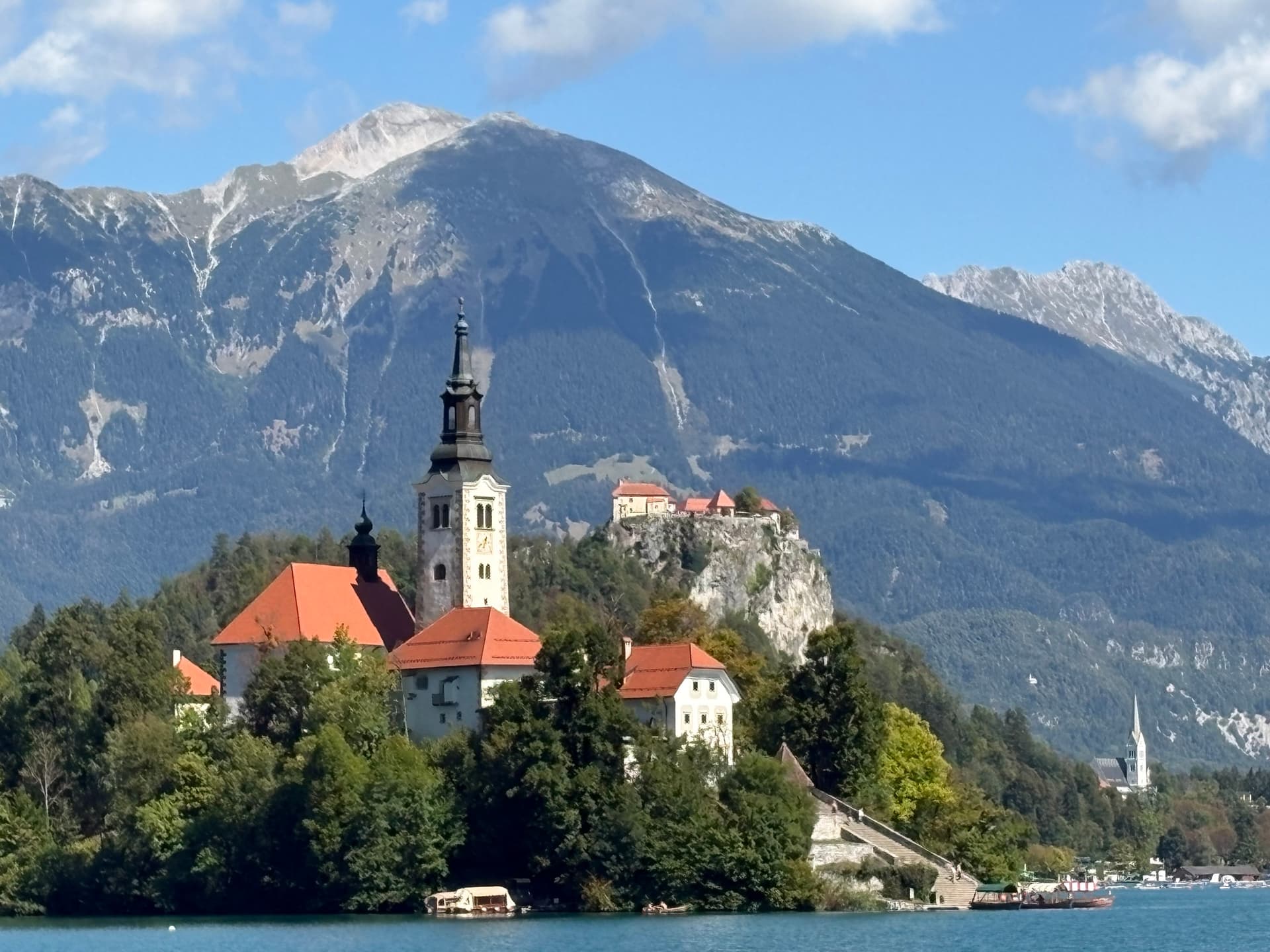 Lake Bled island church with red tile roofs and mountain backdrop