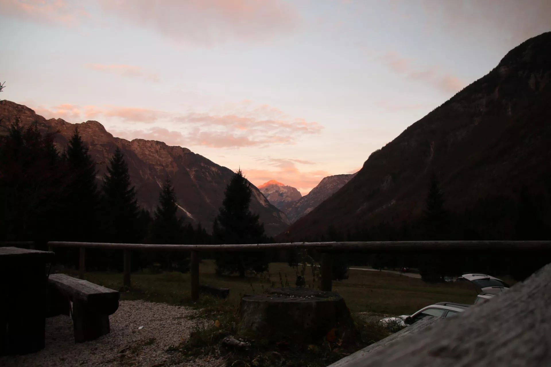 Mountain valley view at sunset with wooden bench and parked cars near Dom Klementa Juga v Lepeni.