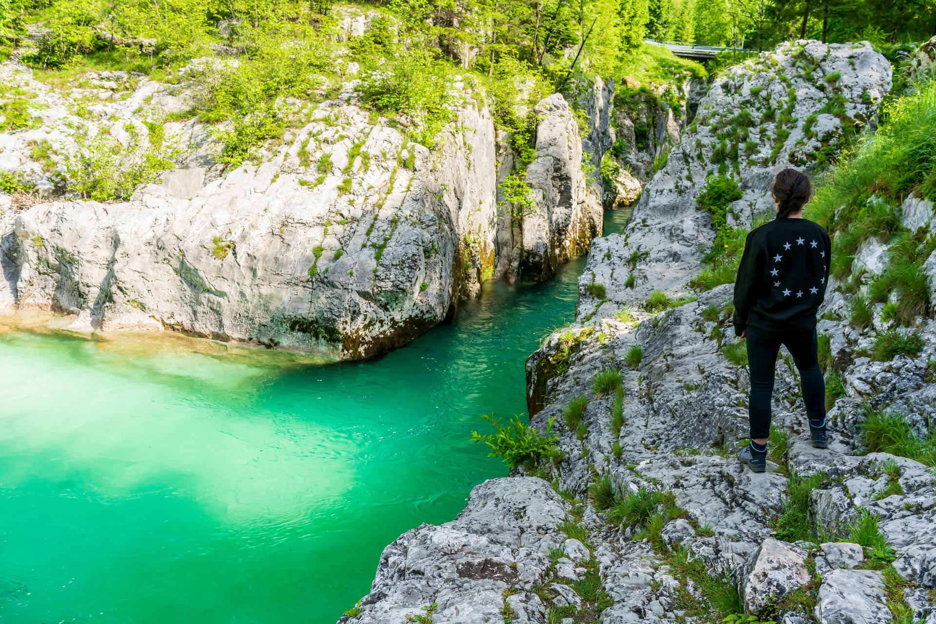 Hiker overlooking turquoise river flowing through rocky gorge in Soca Valley