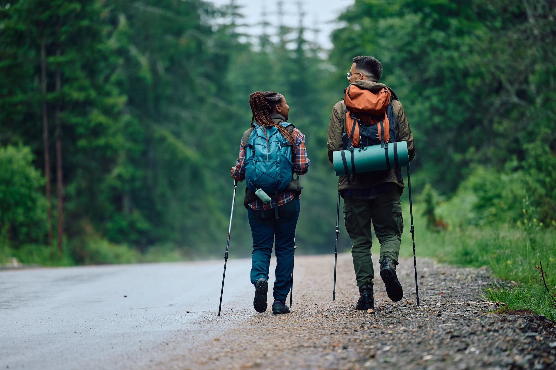Achteraanzicht van backpackers die langs de weg in de natuur wandelen.