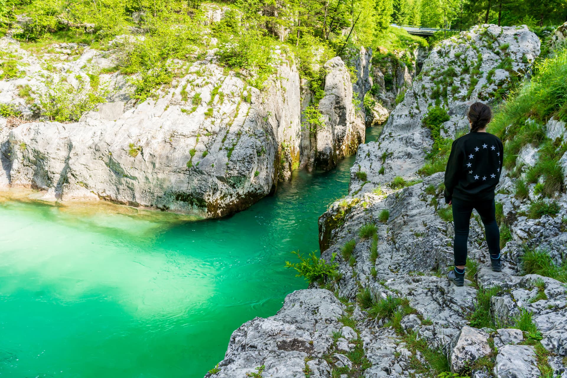Hiker overlooking turquoise river flowing through rocky gorge in Soca Valley