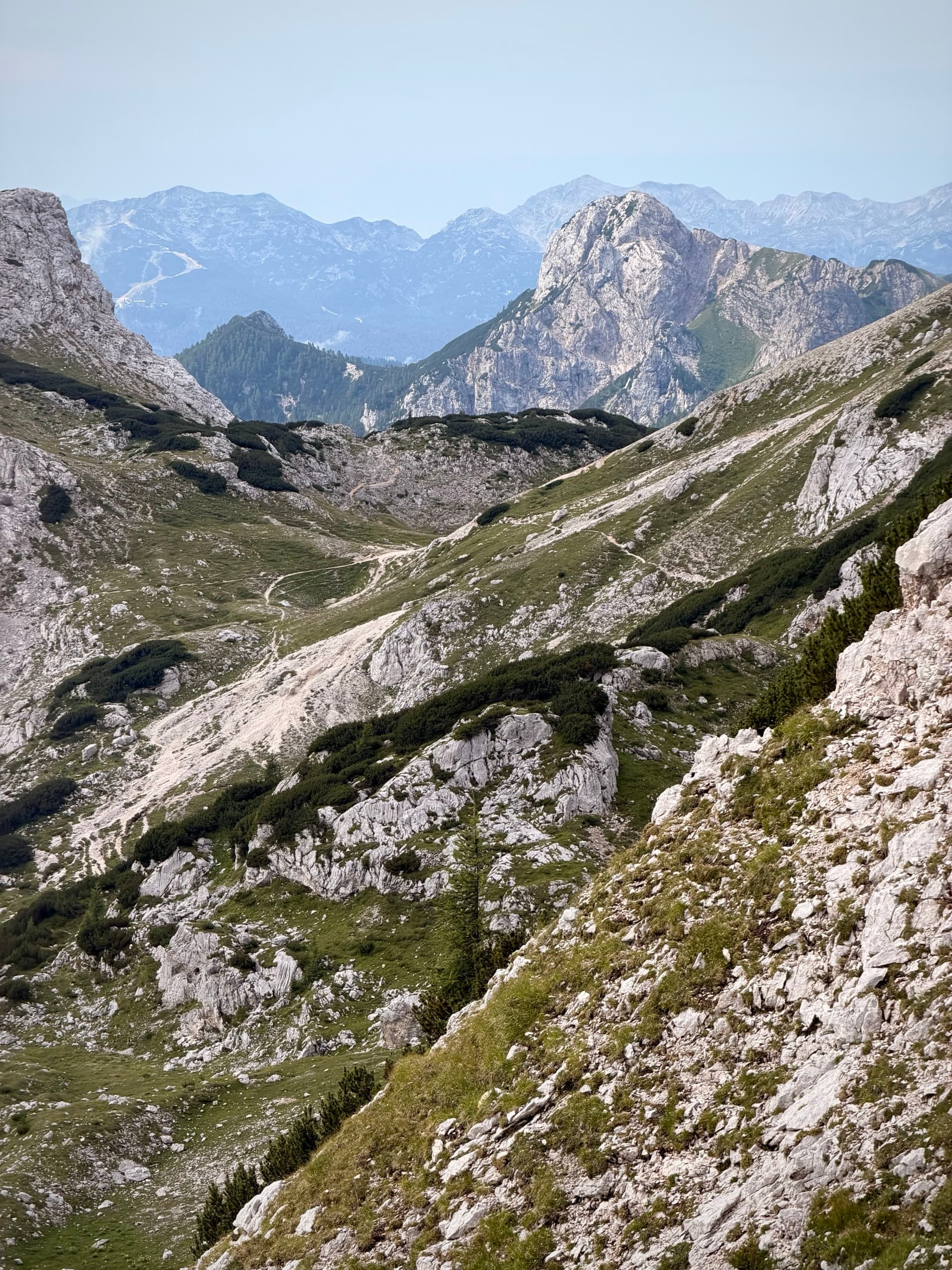 Limestone valley with rocky slopes below a pointed peak in alpine mountains