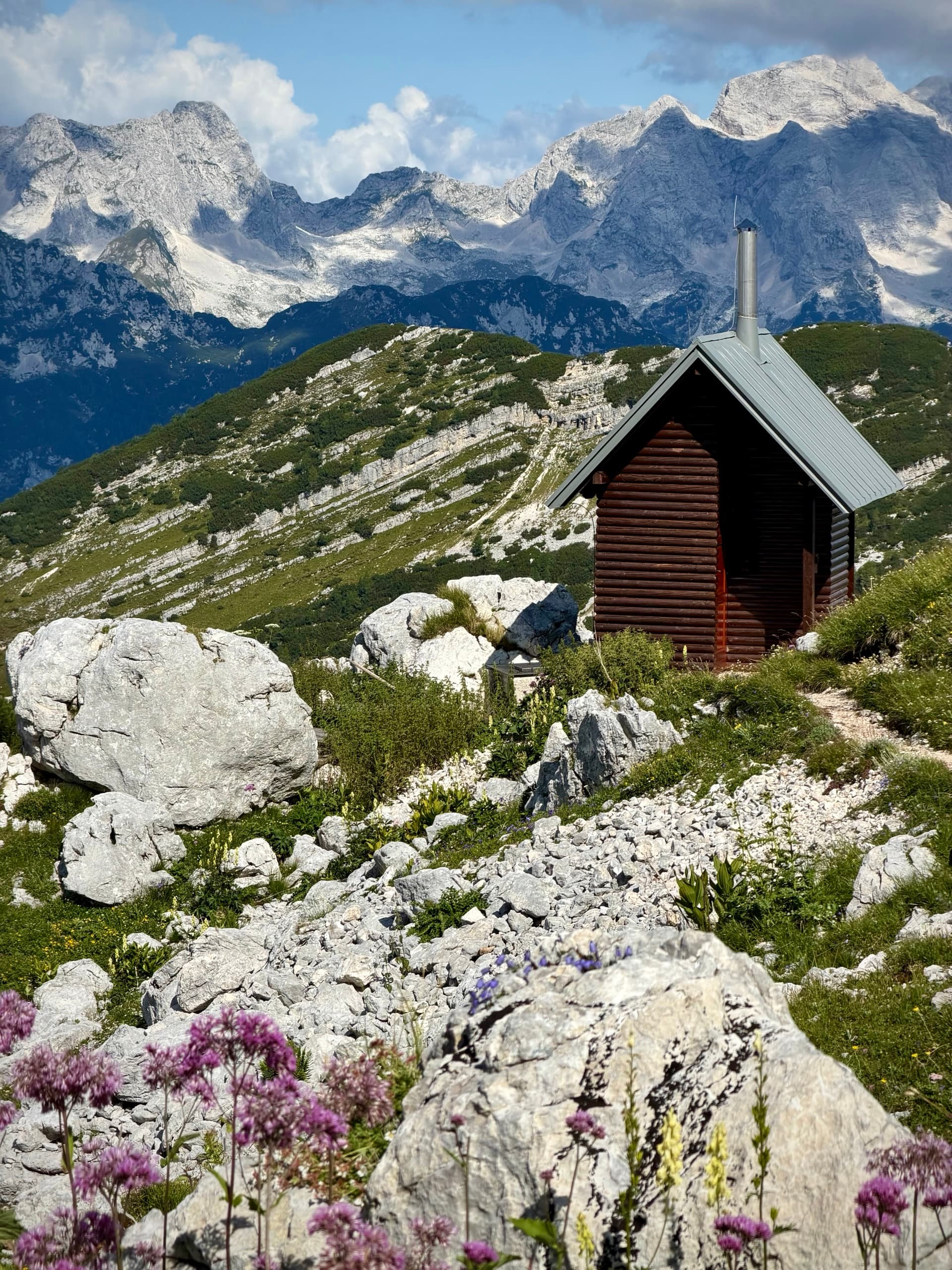 Wooden shelter below snowy mountain peaks in alpine landscape