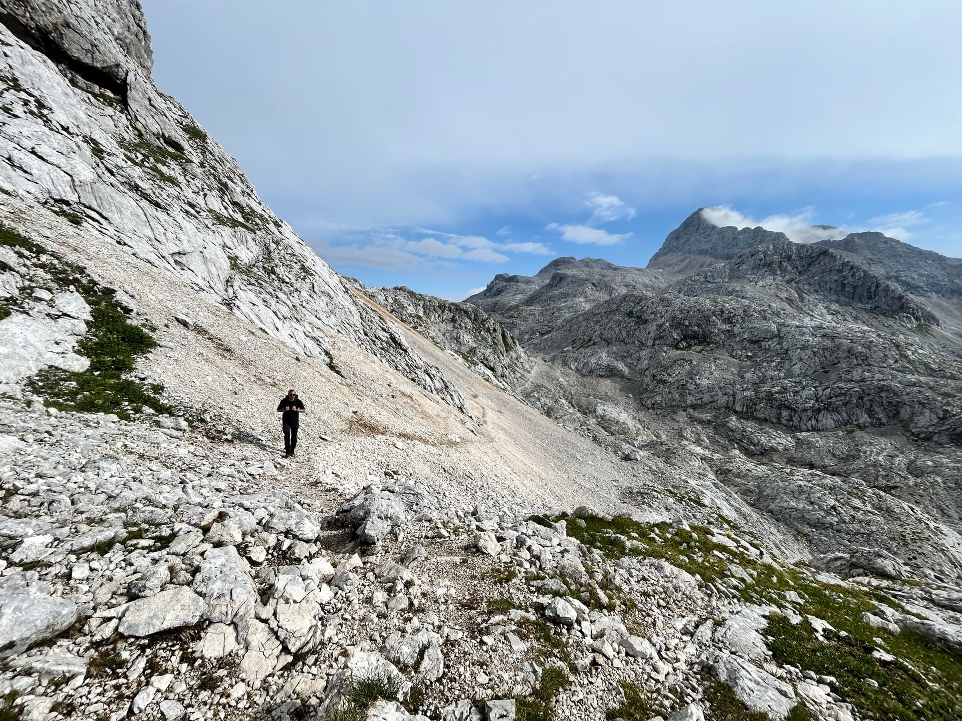 Hiker on rocky scree path below alpine summit