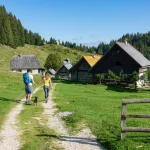 unrecognizable,man,and,woman,walk,toward,a,village,of,wooden