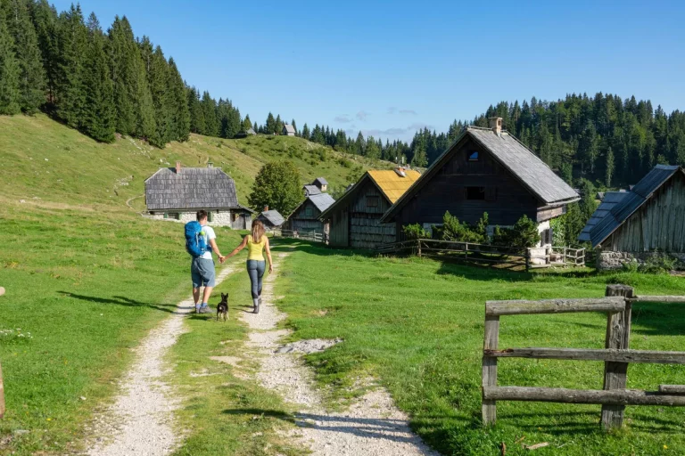 unrecognizable,man,and,woman,walk,toward,a,village,of,wooden