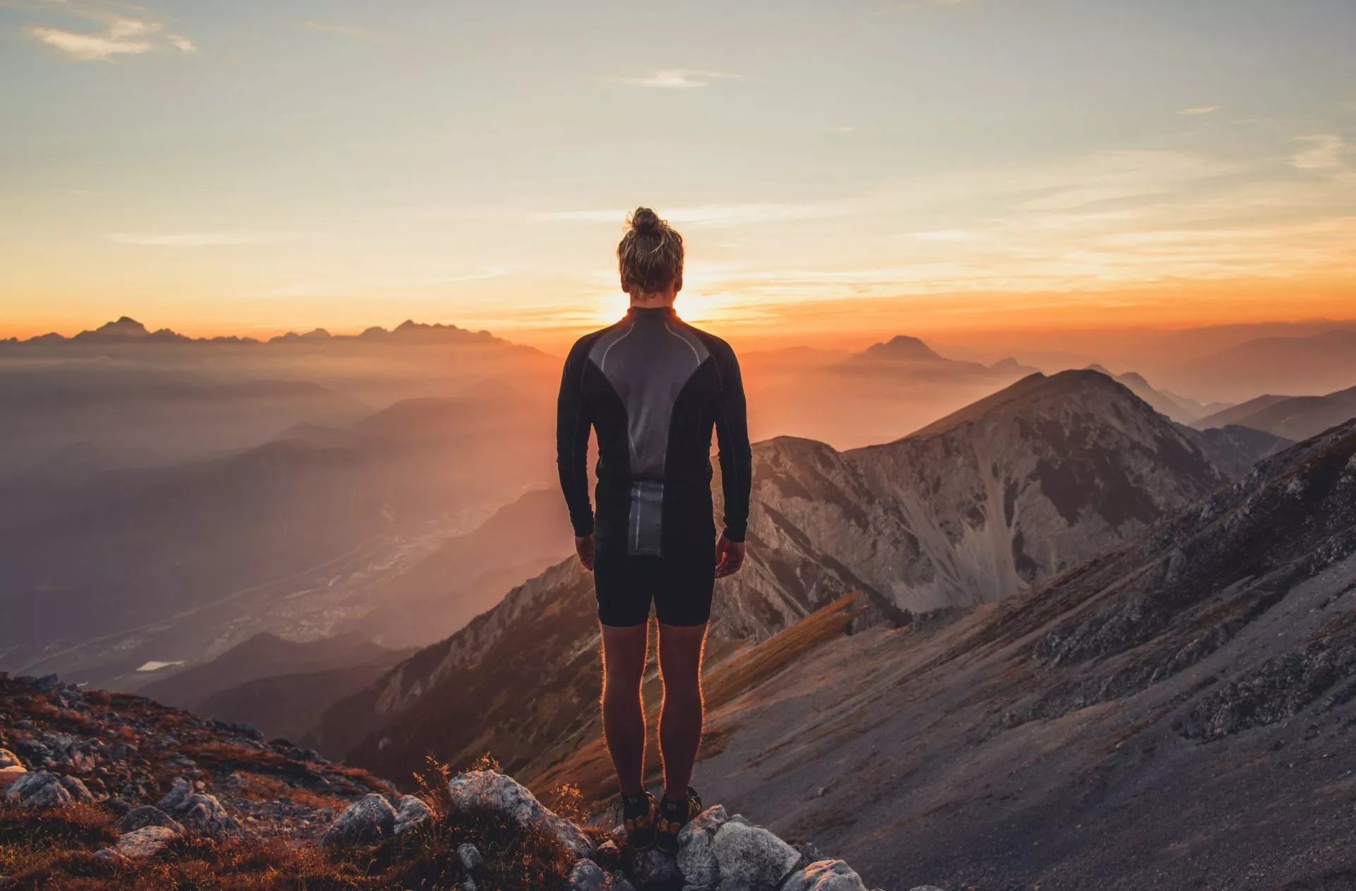 male hiker observing the sunset at the top of the local big moun